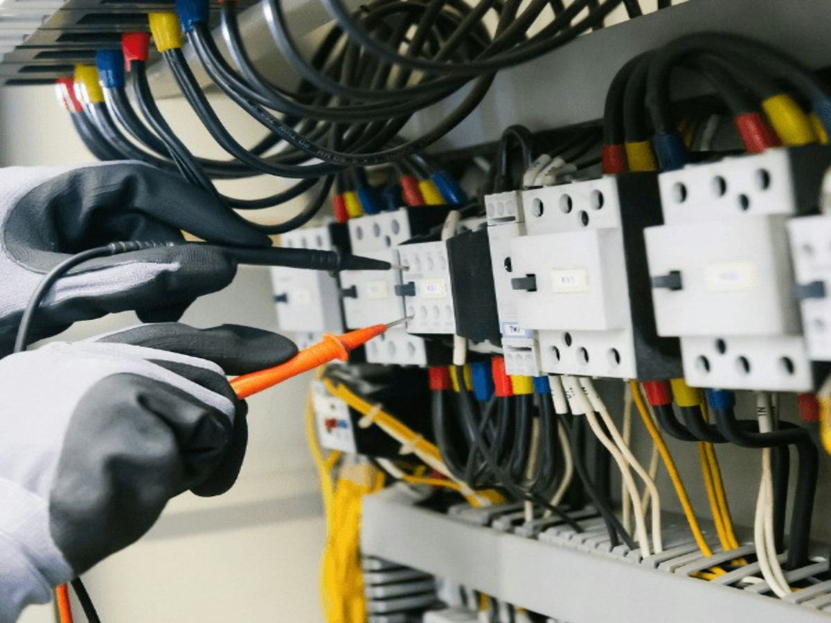 Electrician testing circuit breakers with a voltage tester